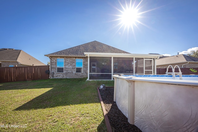 back of property with a yard, a fenced in pool, and a sunroom