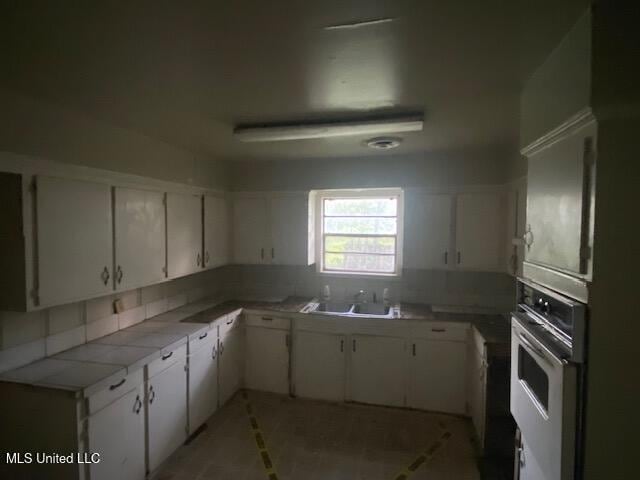 511 Forest Ave, Jackson, MS 39206 - kitchen featuring white oven, a sink, white cabinets, and tile counters