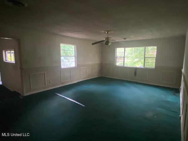 511 Forest Ave, Jackson, MS 39206 - spare room with dark colored carpet, wainscoting, plenty of natural light, a ceiling fan, and a decorative wall