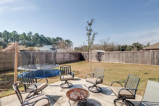 view of patio with a fire pit, a trampoline, and a fenced backyard