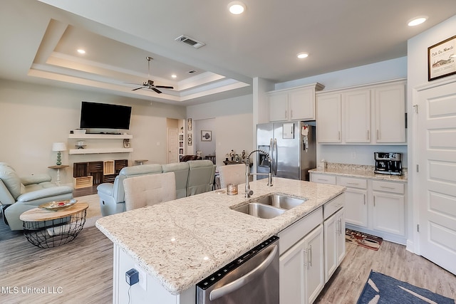 kitchen featuring white cabinets, stainless steel appliances, a sink, and open floor plan