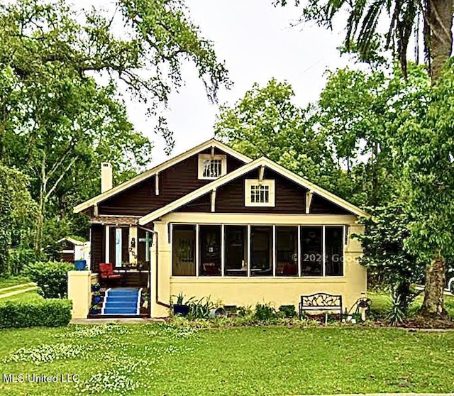 208 Washington Ave, Ocean Springs, MS 39564 - rear view of property with a sunroom, a lawn, a chimney, and stucco siding