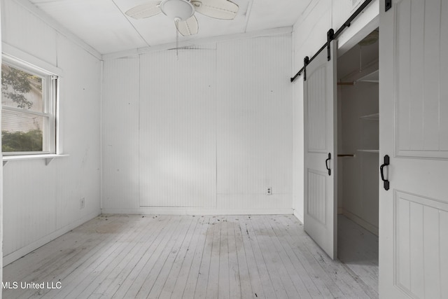 208 Washington Ave, Ocean Springs, MS 39564 - unfurnished bedroom featuring a barn door and light wood finished floors