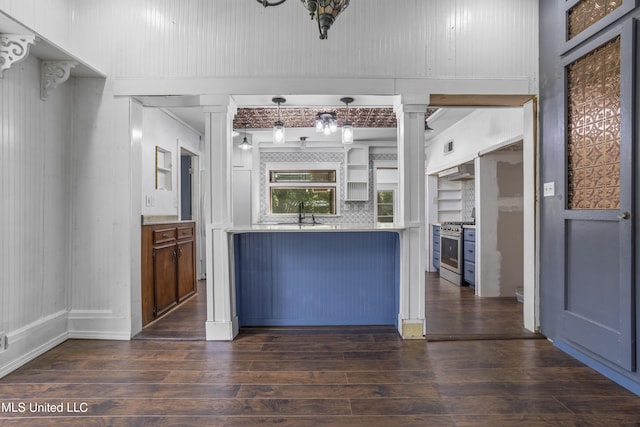 208 Washington Ave, Ocean Springs, MS 39564 - kitchen with stainless steel gas range, dark wood-style floors, light countertops, a decorative wall, and backsplash