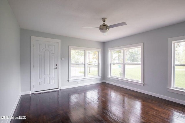 empty room featuring a wealth of natural light, dark hardwood / wood-style floors, and ceiling fan