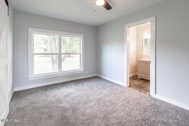 unfurnished bedroom featuring ensuite bathroom, light colored carpet, and ceiling fan