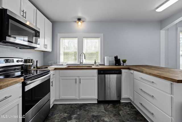 kitchen with white cabinetry, wooden counters, stainless steel appliances, and sink