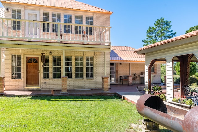 rear view of house with a patio, a lawn, and a balcony