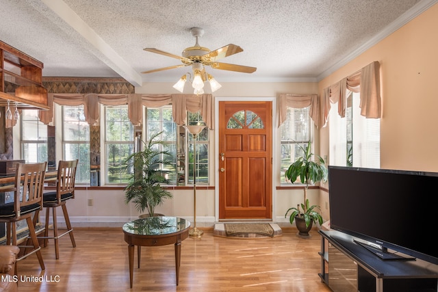 interior space with ceiling fan, a textured ceiling, hardwood / wood-style flooring, beamed ceiling, and crown molding