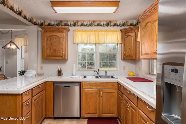 kitchen featuring kitchen peninsula, a textured ceiling, stainless steel appliances, and sink