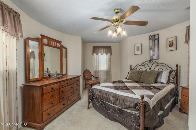 bedroom featuring ceiling fan, a textured ceiling, and light colored carpet