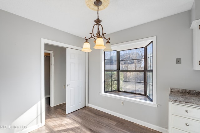 unfurnished dining area with hardwood / wood-style flooring and a chandelier