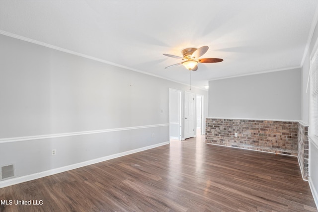 spare room featuring crown molding, brick wall, dark hardwood / wood-style floors, and ceiling fan