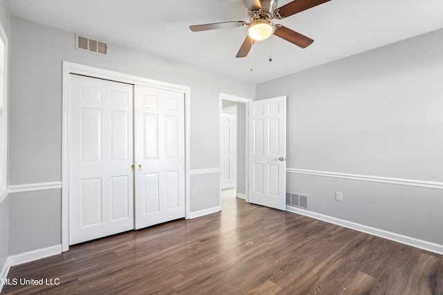 unfurnished bedroom with ceiling fan, dark hardwood / wood-style flooring, and a closet