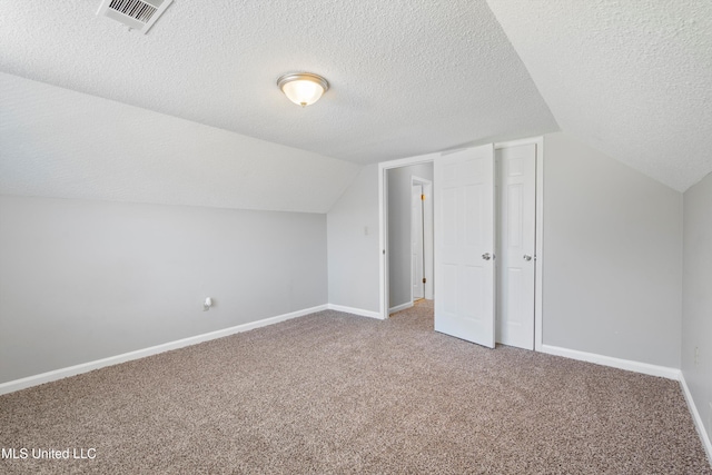 additional living space featuring lofted ceiling, carpet flooring, and a textured ceiling