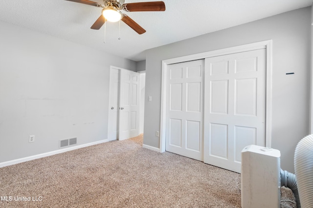 unfurnished bedroom with ceiling fan, light carpet, and a textured ceiling