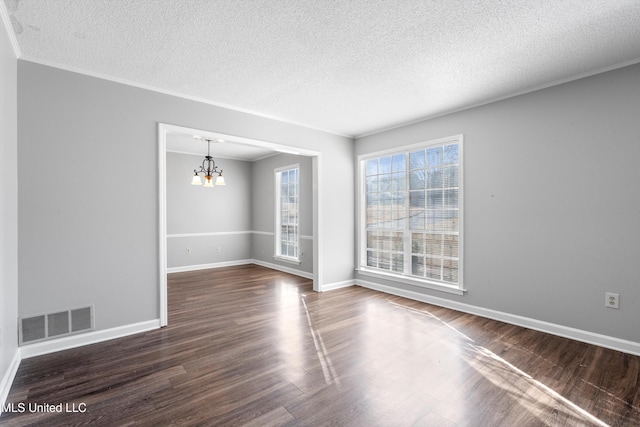 spare room featuring an inviting chandelier, crown molding, dark wood-type flooring, and a textured ceiling