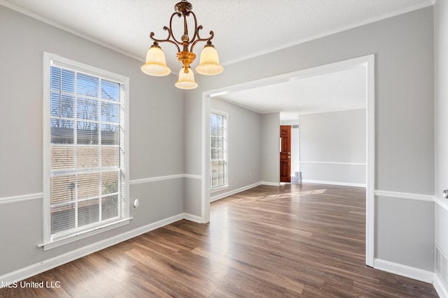 empty room featuring crown molding, dark hardwood / wood-style floors, a chandelier, and a textured ceiling