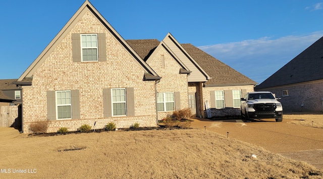 view of front of house with a shingled roof and brick siding