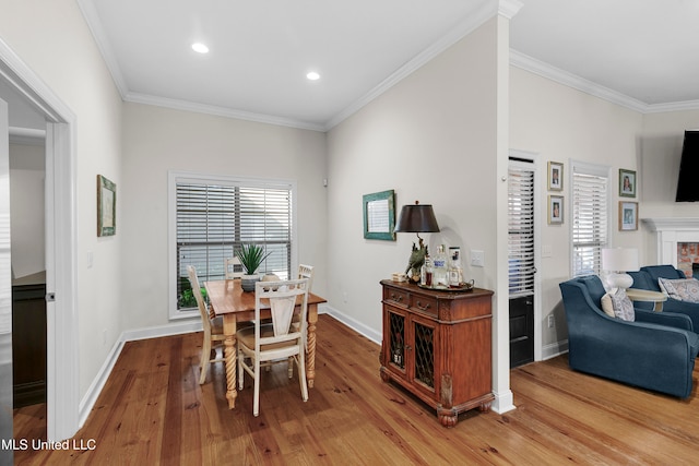 dining room featuring a brick fireplace, hardwood / wood-style floors, and ornamental molding