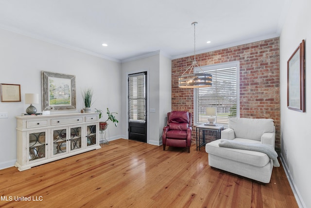 sitting room with a notable chandelier, light wood-type flooring, and crown molding