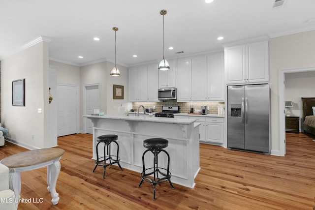 kitchen with hanging light fixtures, white cabinetry, light hardwood / wood-style flooring, and stainless steel appliances