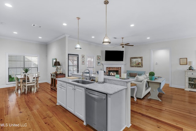 kitchen with white cabinetry, sink, light hardwood / wood-style flooring, stainless steel dishwasher, and decorative light fixtures