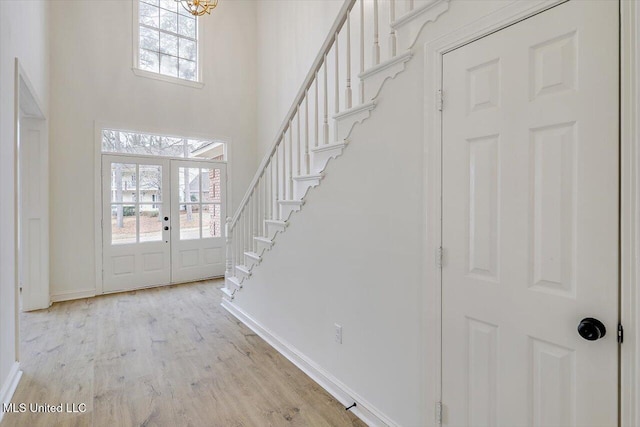 entryway featuring a towering ceiling, light hardwood / wood-style floors, and french doors