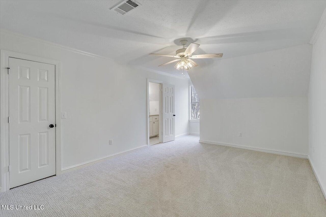 bonus room with ceiling fan, vaulted ceiling, light colored carpet, and a textured ceiling