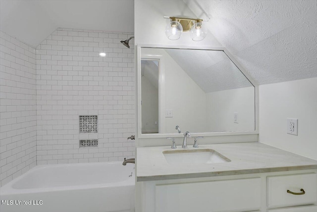 bathroom with vanity, vaulted ceiling, a textured ceiling, and tiled shower / bath