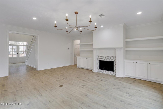 unfurnished living room featuring a tile fireplace, light hardwood / wood-style floors, crown molding, built in shelves, and french doors