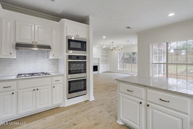 kitchen featuring ornamental molding, white cabinets, stainless steel appliances, light hardwood / wood-style floors, and backsplash