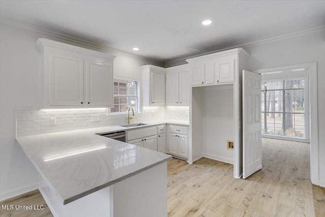 kitchen featuring sink, ornamental molding, kitchen peninsula, light hardwood / wood-style floors, and white cabinets