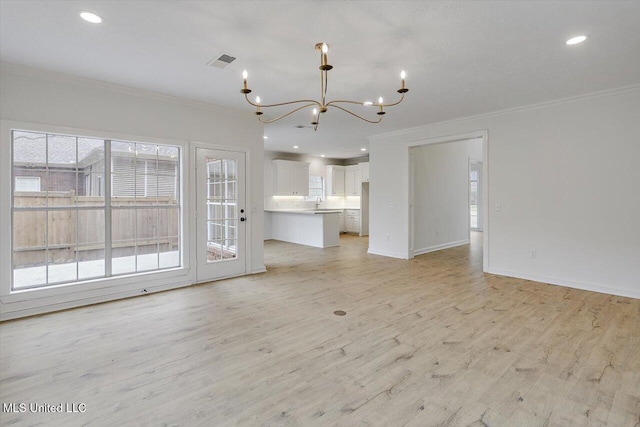 unfurnished living room featuring ornamental molding, light hardwood / wood-style floors, and a notable chandelier