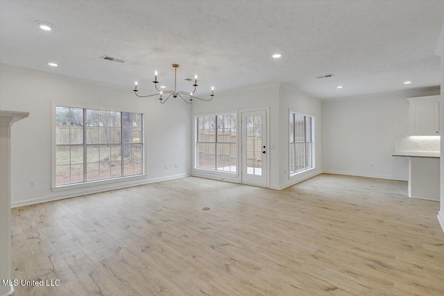 unfurnished living room with an inviting chandelier, ornamental molding, light hardwood / wood-style floors, and a textured ceiling