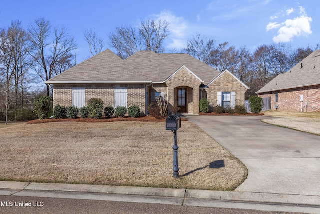 french country style house featuring a shingled roof and brick siding