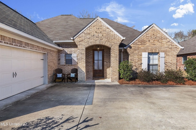 view of front of home with a garage, brick siding, and a shingled roof