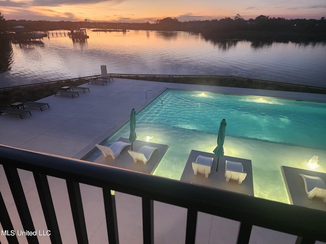 pool at dusk featuring a water view