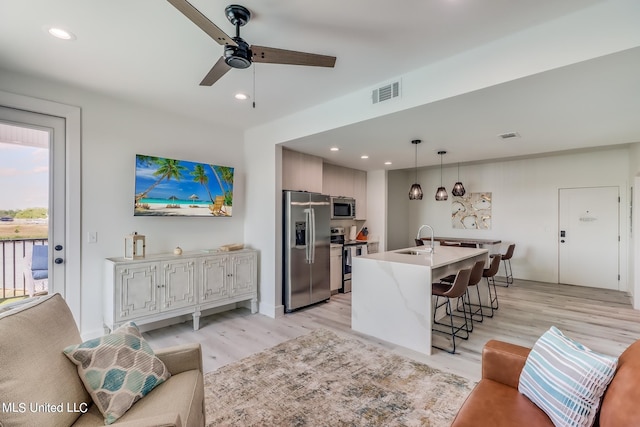 living room featuring light hardwood / wood-style flooring, sink, and ceiling fan