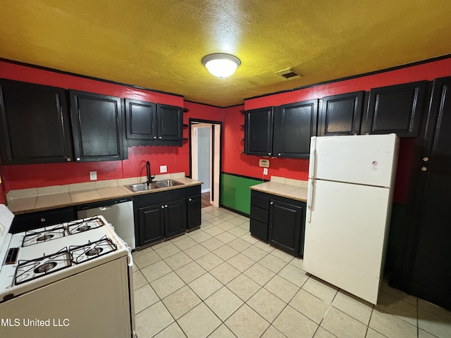 3258 Meadow Ln, Jackson, MS 39212 - kitchen with white appliances, a textured ceiling, tile counters, dark cabinetry, and light tile patterned floors