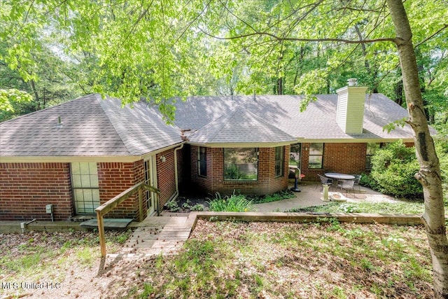 7488 Hickory Estates Dr, Walls, MS 38680 - view of front of house featuring brick siding, a shingled roof, a patio area, and a chimney