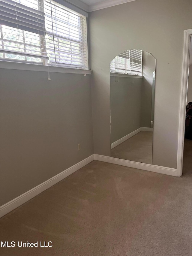 unfurnished bedroom featuring carpet, baseboards, and crown molding