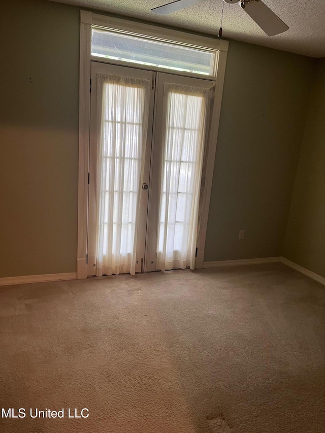 spare room featuring a textured ceiling, light carpet, baseboards, and a ceiling fan
