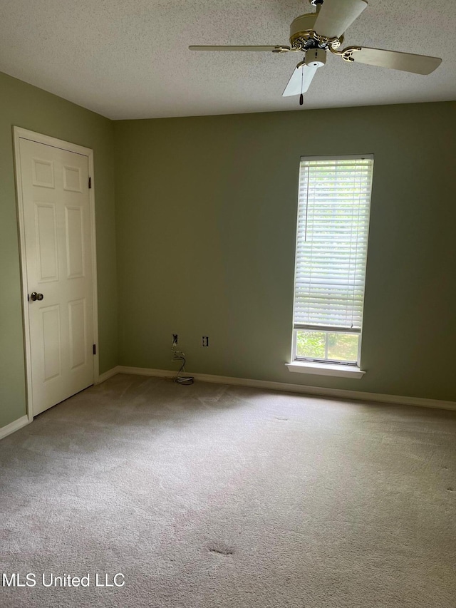 carpeted empty room featuring a textured ceiling, baseboards, and ceiling fan