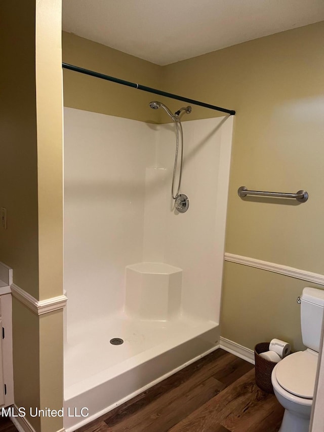 full bathroom featuring toilet, baseboards, a shower, and wood finished floors