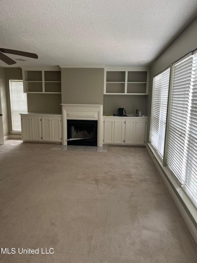unfurnished living room featuring a textured ceiling, light carpet, and a healthy amount of sunlight
