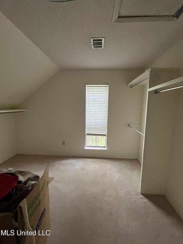 additional living space featuring vaulted ceiling, carpet flooring, and visible vents