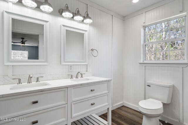 bathroom featuring double vanity, a sink, toilet, and wood finished floors