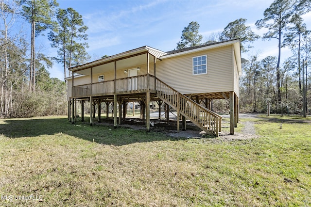 rear view of house featuring stairs and a lawn