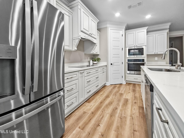 16814 W Landon Green Dr, Gulfport, MS 39503 - kitchen with appliances with stainless steel finishes, white cabinets, light wood finished floors, recessed lighting, and ornamental molding